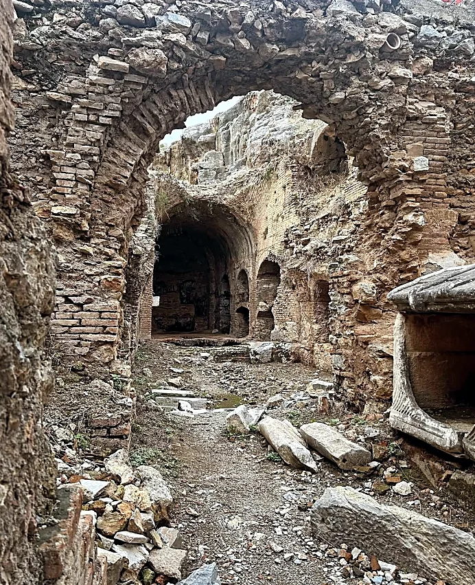 A brick-arched passage in the Seven Sleepers ruins, with vaulted chambers and fallen marble blocks beyond